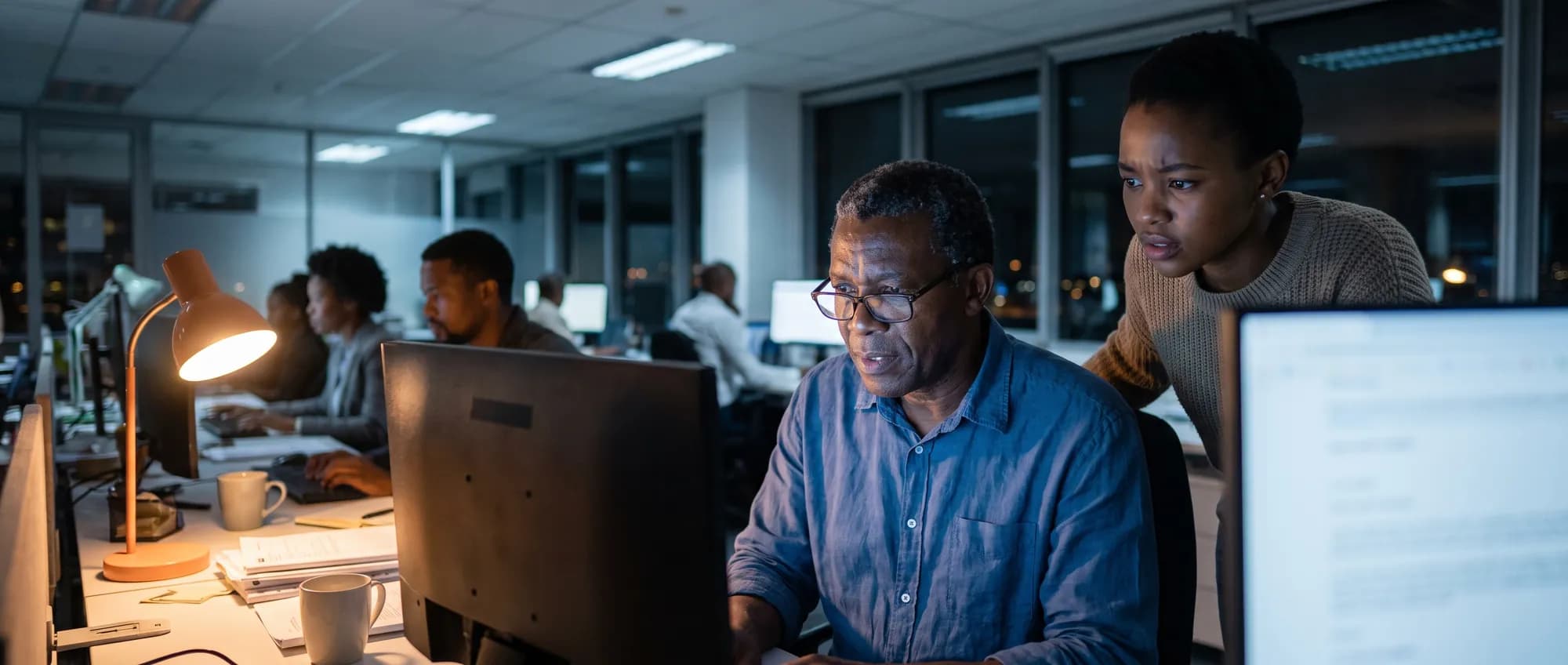 A finance officer and colleague checking a suspicious email in the evening